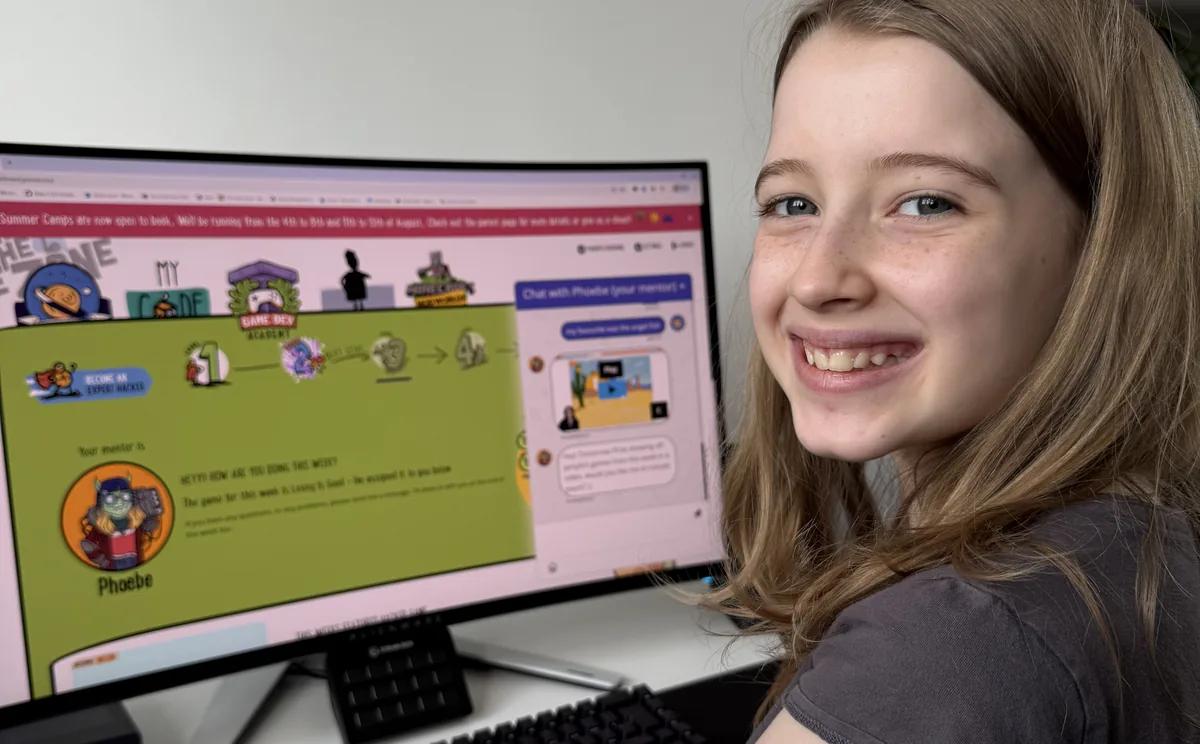 A Game Dev Club member at her own computer, turning from the screen where her mentor Phoebe has set this week's game